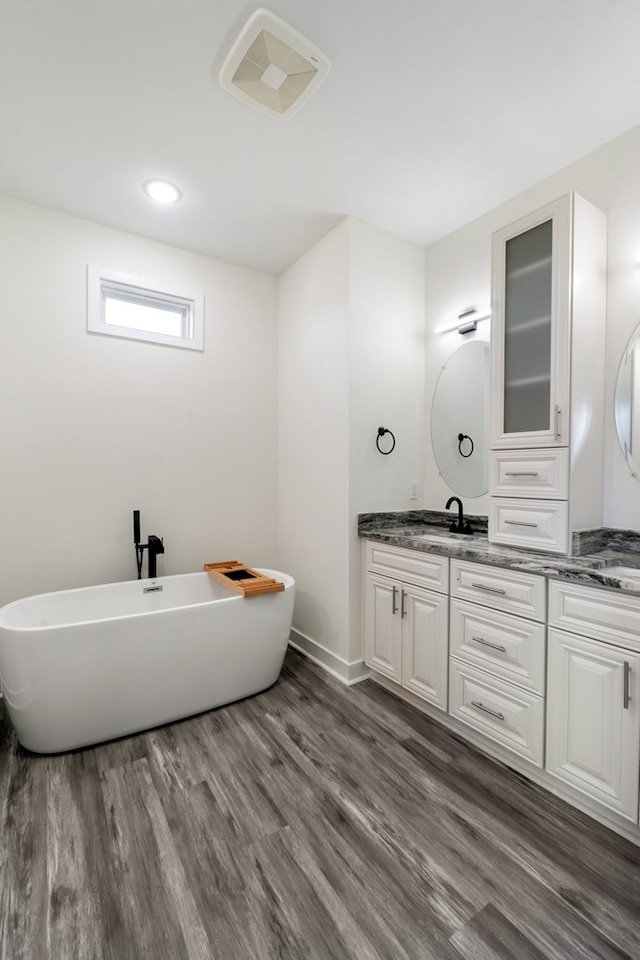 bathroom featuring hardwood / wood-style flooring, vanity, and a tub to relax in