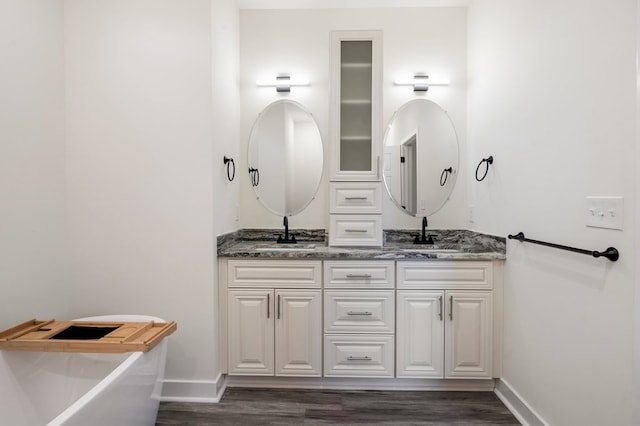 bathroom with hardwood / wood-style floors, vanity, and a tub to relax in