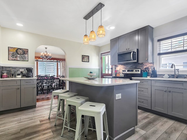 kitchen with gray cabinets, a kitchen island, sink, and appliances with stainless steel finishes