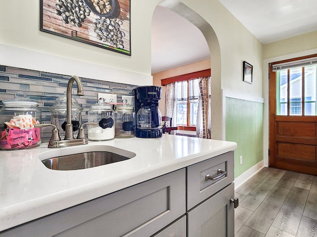 kitchen featuring gray cabinetry, decorative backsplash, sink, and light hardwood / wood-style flooring