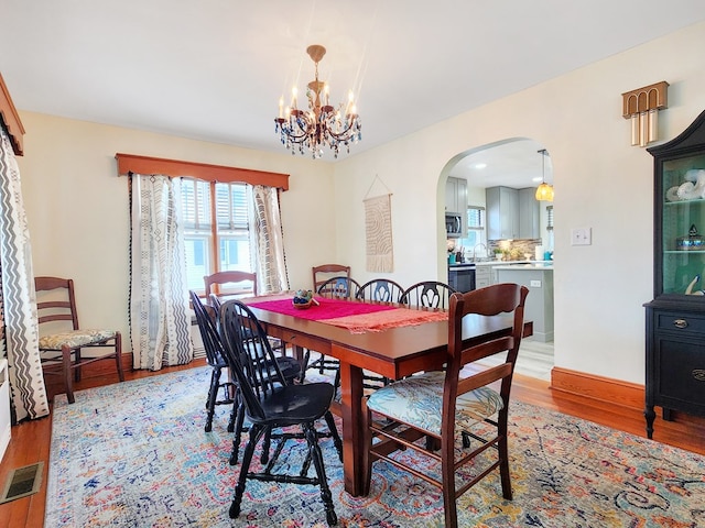 dining area with light wood-type flooring and an inviting chandelier