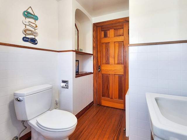 bathroom with toilet, wood-type flooring, and tile walls