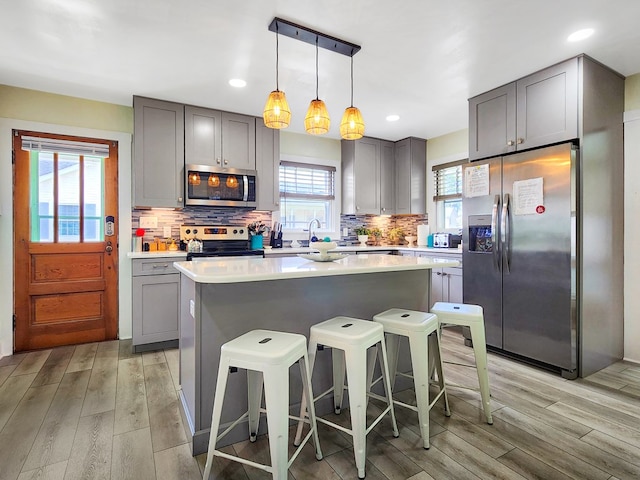 kitchen with gray cabinetry, pendant lighting, and appliances with stainless steel finishes