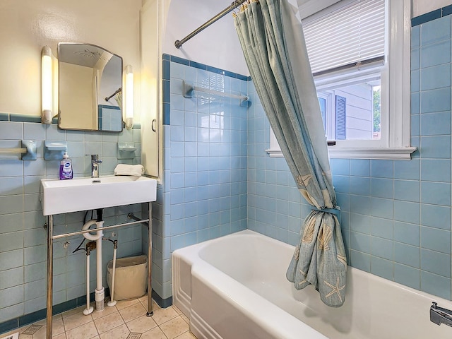 bathroom with tile patterned floors, tile walls, shower / bath combo with shower curtain, and sink