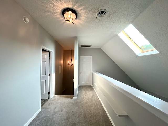 corridor with carpet and vaulted ceiling with skylight