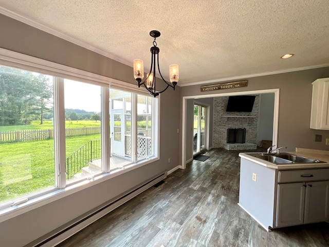 kitchen featuring pendant lighting, a baseboard heating unit, an inviting chandelier, sink, and white cabinetry