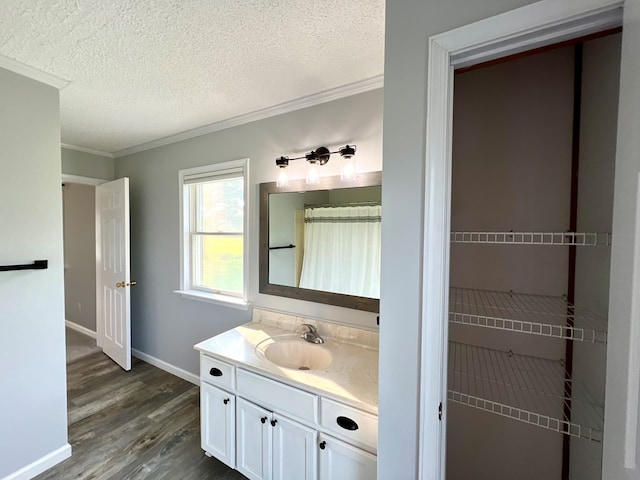 bathroom featuring wood-type flooring, vanity, a textured ceiling, and crown molding