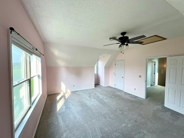 bonus room with carpet, a textured ceiling, vaulted ceiling, and ceiling fan