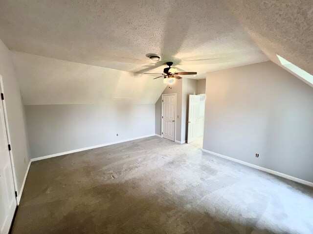 bonus room featuring a textured ceiling, carpet floors, lofted ceiling with skylight, and ceiling fan