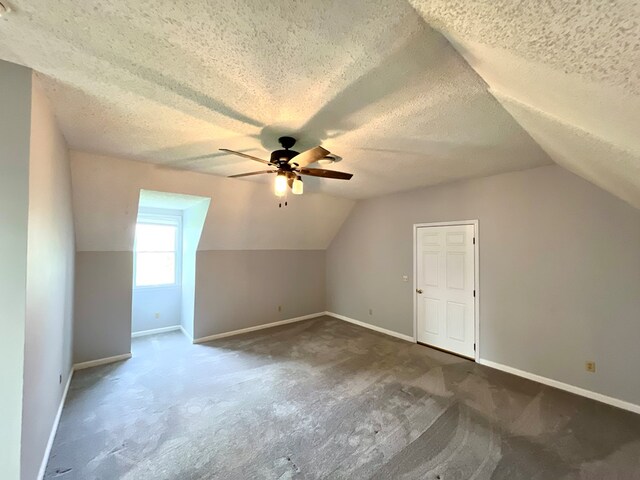 bonus room with a textured ceiling, dark carpet, ceiling fan, and lofted ceiling