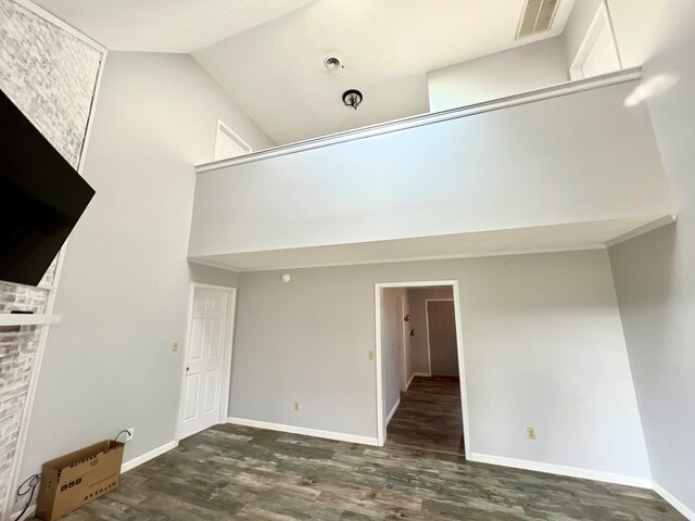 unfurnished living room featuring a towering ceiling and dark hardwood / wood-style floors