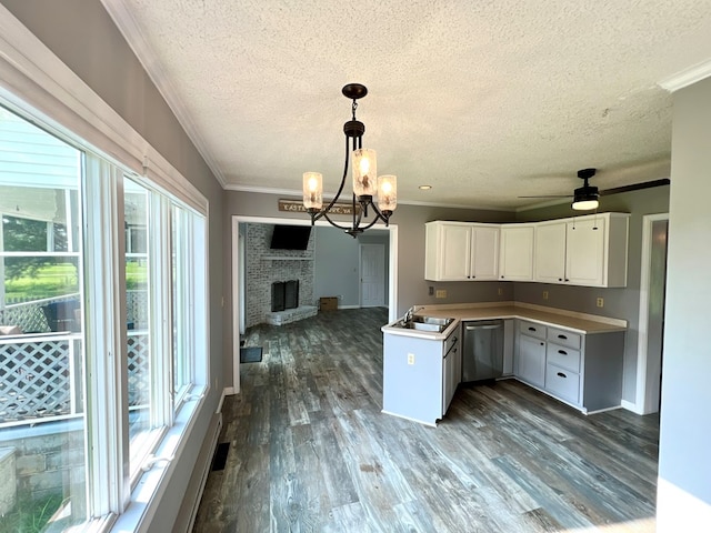 kitchen with a brick fireplace, stainless steel dishwasher, sink, white cabinets, and hanging light fixtures