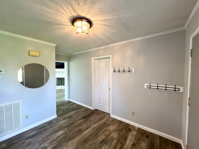 empty room with crown molding, dark hardwood / wood-style floors, a textured ceiling, and a brick fireplace