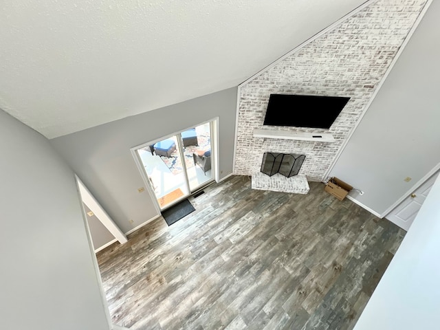 unfurnished living room featuring a textured ceiling, dark hardwood / wood-style flooring, a fireplace, and vaulted ceiling