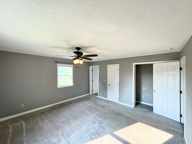 unfurnished bedroom with dark colored carpet, ceiling fan, a textured ceiling, and multiple closets