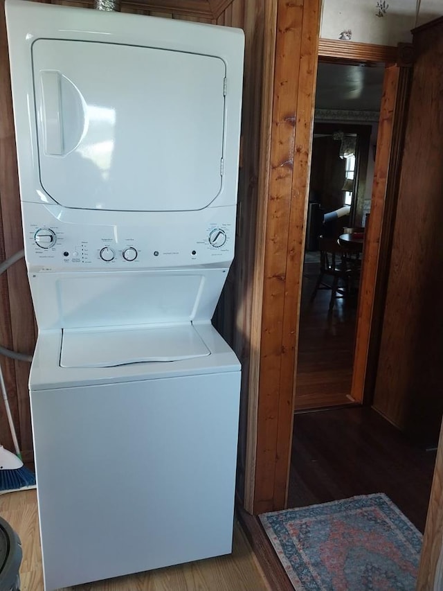 laundry room featuring hardwood / wood-style flooring and stacked washing maching and dryer