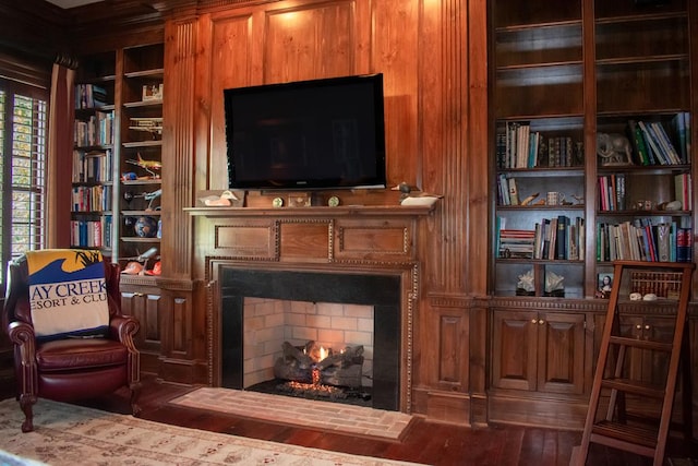 living area with a warm lit fireplace and wood finished floors