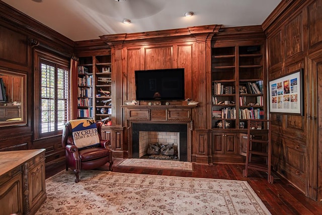 sitting room featuring dark wood-type flooring, built in features, a fireplace, and wood walls