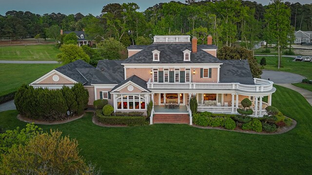 rear view of property featuring a lawn, a balcony, and a porch