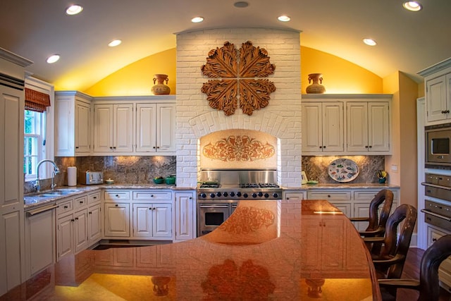 kitchen with a sink, stainless steel appliances, lofted ceiling, and light stone countertops