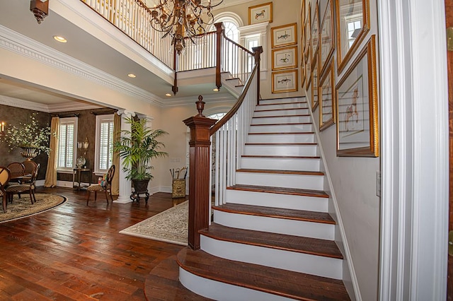 staircase with baseboards, a chandelier, ornamental molding, ornate columns, and wood-type flooring