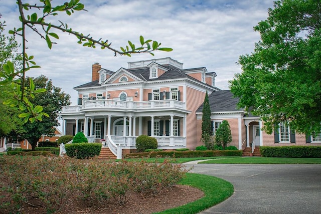 view of front of house with a porch, a chimney, and a balcony