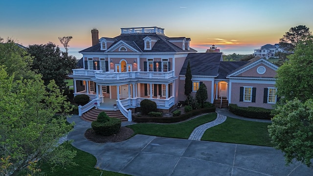 victorian home with a front yard, a balcony, covered porch, and a chimney