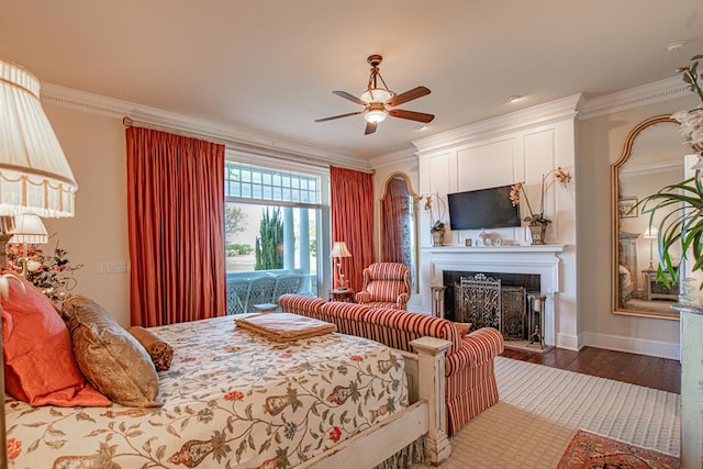 bedroom with a ceiling fan, wood finished floors, a fireplace, crown molding, and baseboards