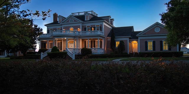 view of front of property featuring a balcony, covered porch, and a chimney