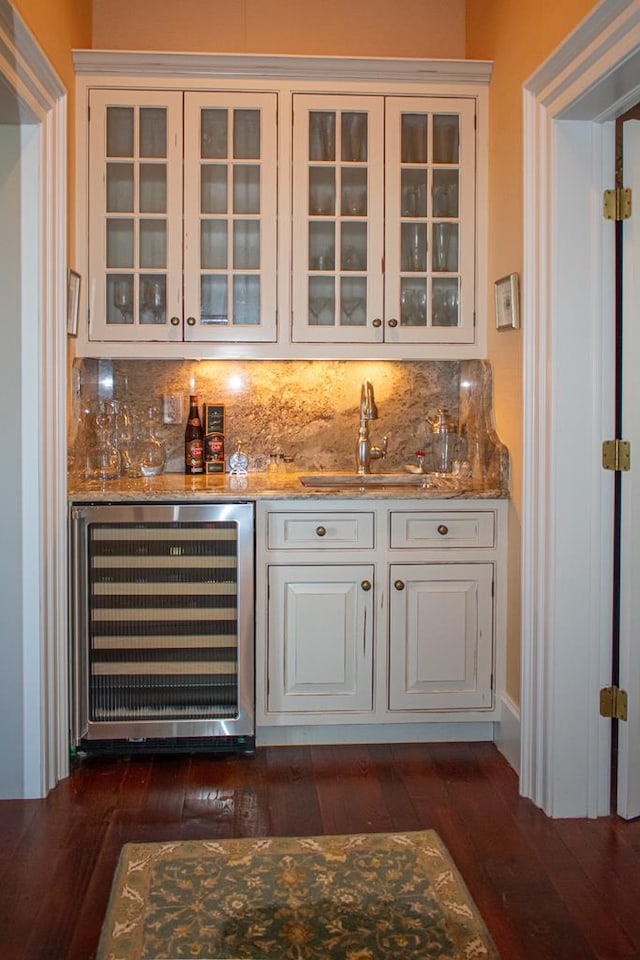 bar with a sink, backsplash, dark wood finished floors, wine cooler, and indoor wet bar