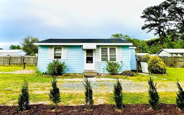 view of front of home with entry steps, a front lawn, and fence