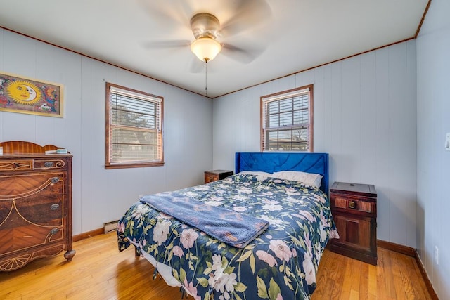 bedroom featuring multiple windows, a baseboard radiator, wood finished floors, and baseboards