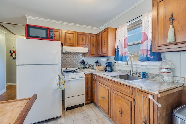 kitchen featuring white appliances, brown cabinetry, light countertops, under cabinet range hood, and a sink