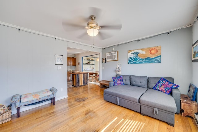 living area with ornamental molding, light wood-type flooring, a ceiling fan, and a wall mounted air conditioner