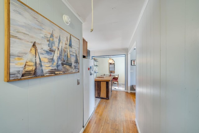 hall with ornamental molding and light wood-type flooring