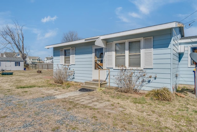 view of front facade with entry steps, fence, and a front lawn