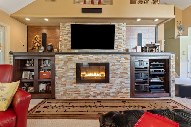 living room with a stone fireplace and lofted ceiling