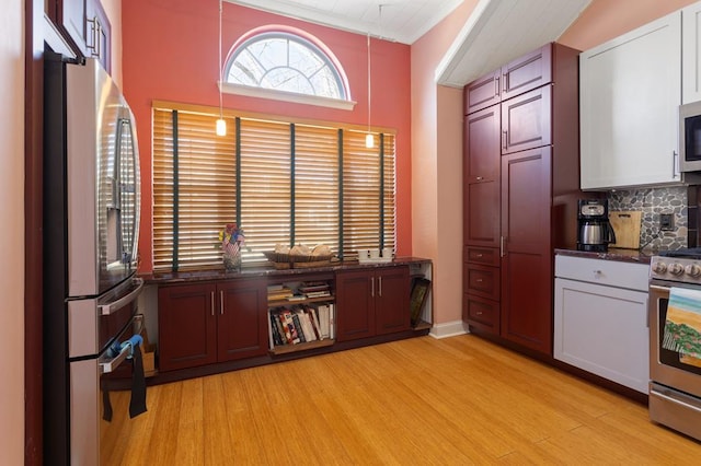 kitchen featuring tasteful backsplash, white cabinetry, hanging light fixtures, appliances with stainless steel finishes, and light hardwood / wood-style floors