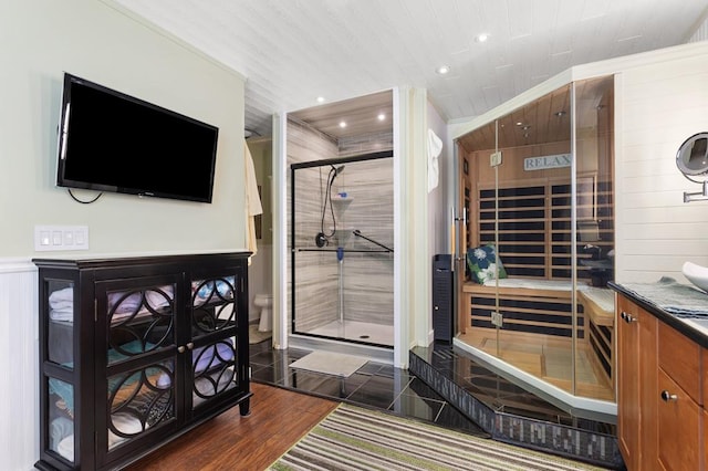 bathroom with hardwood / wood-style floors, vanity, toilet, a shower with door, and crown molding