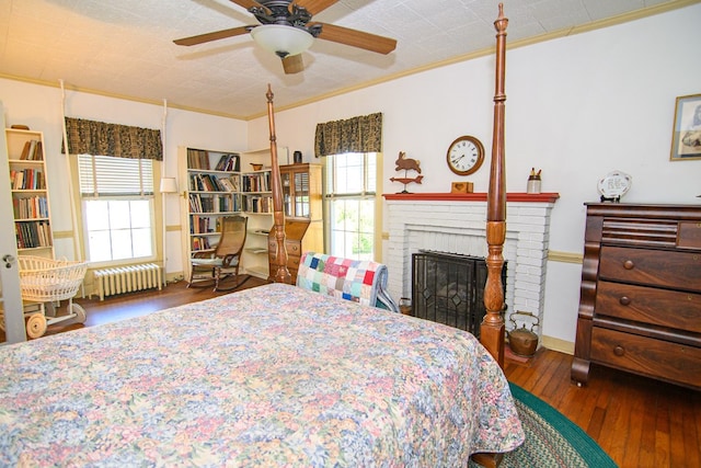 bedroom featuring hardwood / wood-style floors, a brick fireplace, crown molding, and radiator