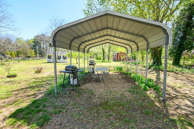 view of car parking with a carport, fence, and a storage unit