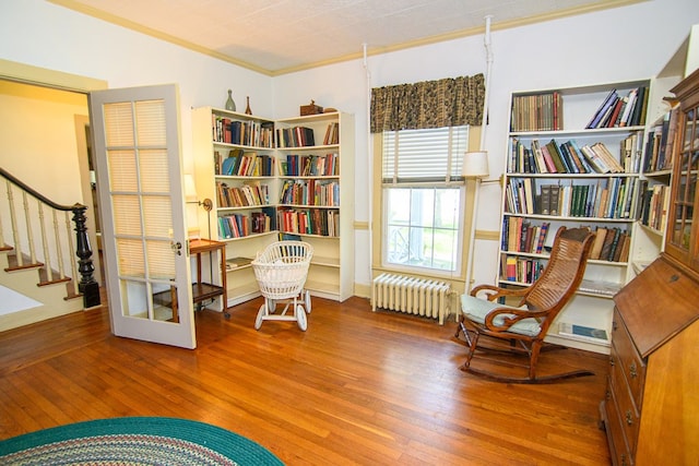 sitting room with radiator heating unit, stairs, hardwood / wood-style flooring, and crown molding