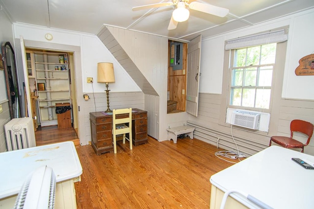 office area with wooden walls, cooling unit, a ceiling fan, radiator, and wood finished floors