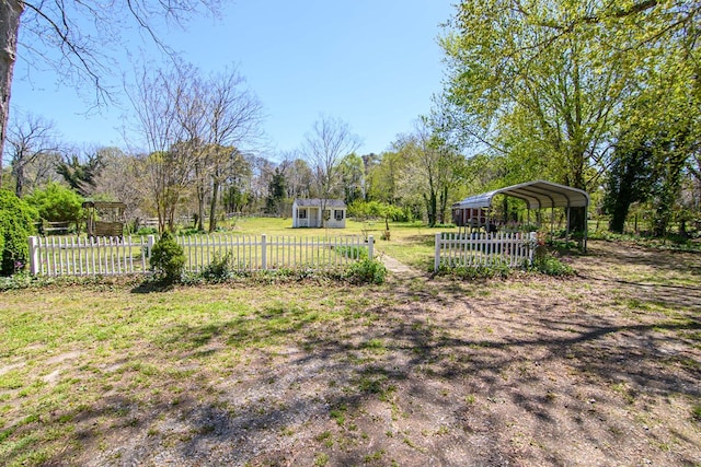 view of yard with a detached carport, fence, and an outdoor structure