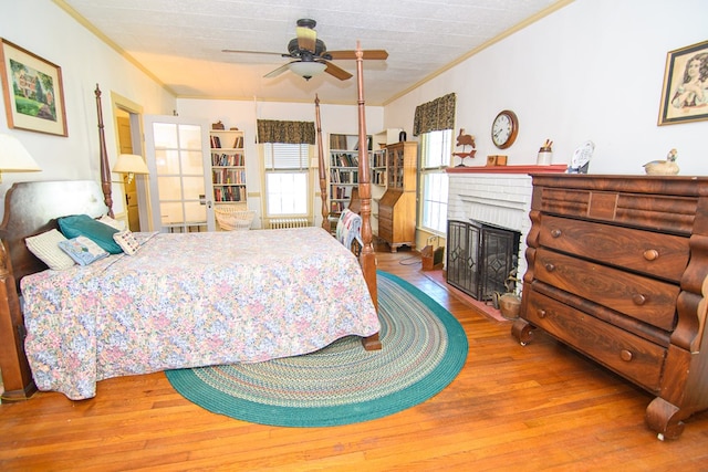bedroom featuring a fireplace, ornamental molding, and wood finished floors