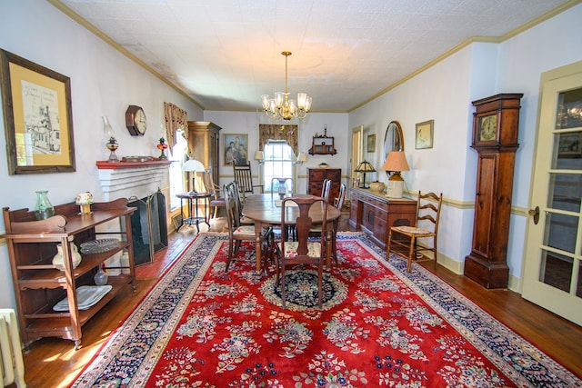 dining area with a fireplace with flush hearth, wood finished floors, an inviting chandelier, and ornamental molding