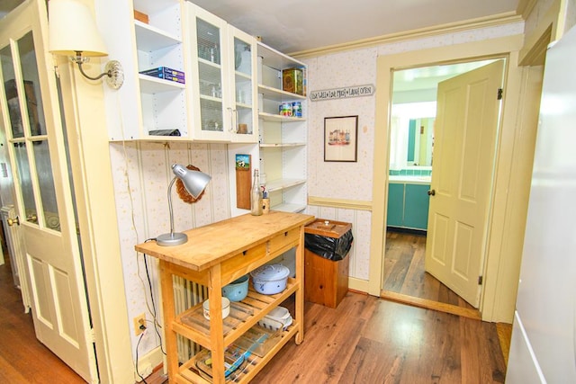 interior space featuring ornamental molding, wood finished floors, and wallpapered walls