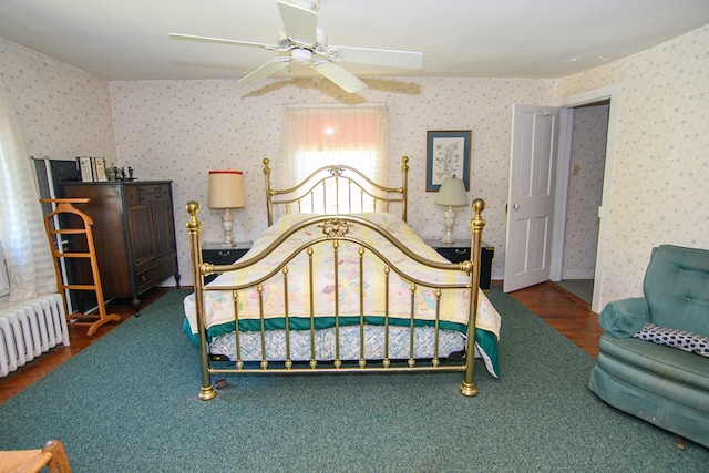bedroom featuring a ceiling fan, radiator, wood finished floors, and wallpapered walls