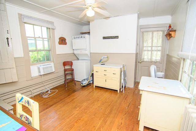 bedroom featuring ornamental molding, cooling unit, a wainscoted wall, stacked washer / dryer, and light wood finished floors
