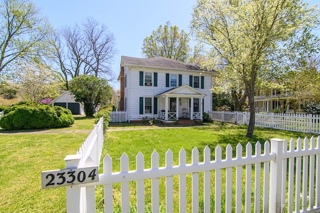 colonial house featuring a fenced front yard, a front yard, and covered porch